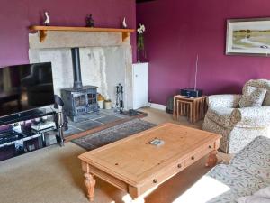 a living room with a fireplace and a coffee table at Birch Cottage- 15841 in Catcleugh