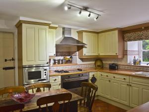 una cocina con armarios amarillos y una mesa con sillas en The Griffin en Broughton in Furness