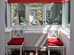 Craven House في West Burton: كرسيين أمام نافذة ذات وسائد حمراء