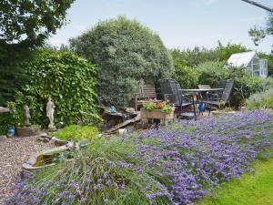 a garden with purple flowers and a table and chairs at Sparrows Nest in Sampford Arundel