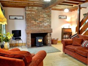 a living room with a brick fireplace and a couch at Stable Cottage - B6062 in Pooley Bridge