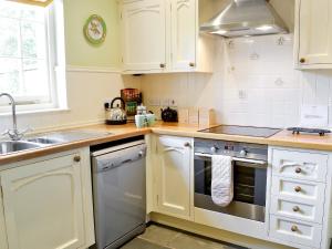 a kitchen with white cabinets and a sink at Garden Cottage in Westleigh