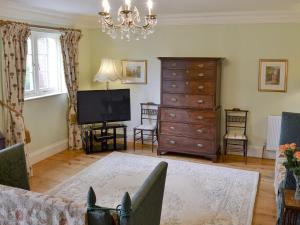 a living room with a television and a dresser at Garden Cottage in Westleigh