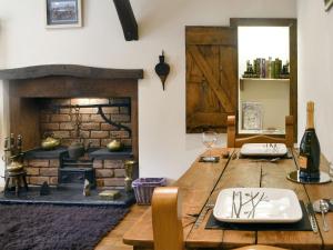 a dining room with a wooden table and a fireplace at The Cottage in Blackwood