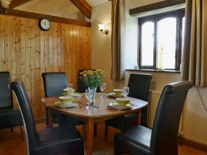 a dining room table with chairs and a clock on the wall at The Stable in Parkham