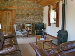 a living room with a leather couch and a wood stove at The Stable in Parkham