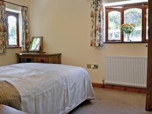 a bedroom with a bed and windows and a television at The Stable in Parkham