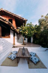 a wooden table with pillows in front of a house at Vila Luz in Caraíva