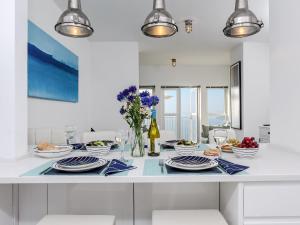 Marina Beach House, Torquay في توركواي: مطبخ أبيض مع طاولة مع أطباق من الطعام