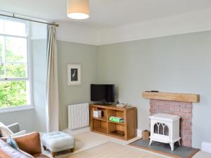 a living room with a fireplace and a tv at 4 The Old Vicarage in Far Sawrey