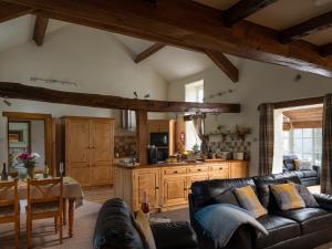a living room with a couch and a kitchen at Plas Iwrwg Granary - 28091 in Tal-y-Cafn