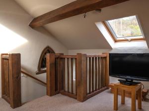 uma sala de estar com uma televisão de ecrã plano e uma clarabóia em Plas Iwrwg Granary - 28091 em Tal-y-Cafn