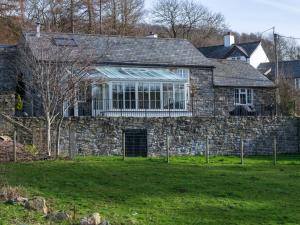 uma grande casa de pedra com uma grande janela em Plas Iwrwg Granary - 28091 em Tal-y-Cafn