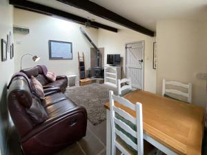 ein Wohnzimmer mit einem Ledersofa und einem Holztisch in der Unterkunft Fell Cottage in Marsett