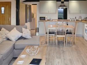 a living room with a couch and a table and a kitchen at Dairy Cottage in Alkham