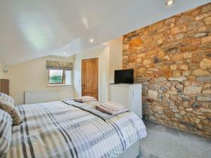 una camera con letto e parete in pietra di Horseshoe Cottage a Bolton by Bowland