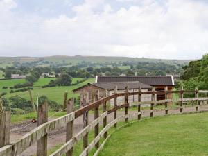 a wooden fence in a field with a barn at Horseshoe Cottage in Bolton by Bowland