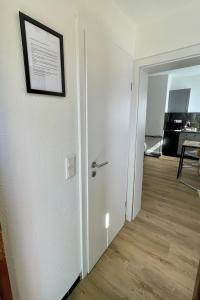 un pasillo con una puerta blanca con una foto en la pared en moor-home Studio Apartment, en Ganderkesee