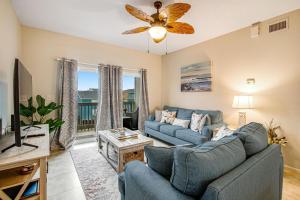 a living room with two blue couches and a tv at Villas on the Gulf J6 in Pensacola Beach