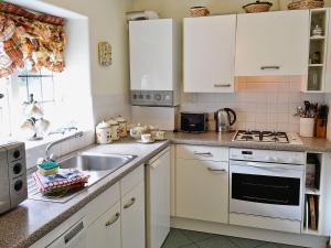 アンブルサイドにあるBlack Combe Apartmentの白いキャビネットとシンク付きのキッチン