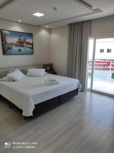 um quarto com uma cama e uma grande janela em Hotel Serrano em Frederico Westphalen