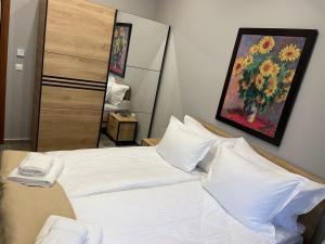 um quarto com uma cama branca e uma pintura na parede em Вила Рафаела-Мартина em Dobrinishte