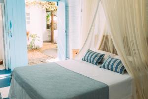 a bedroom with a bed with blue and white pillows at Vila Luz in Caraíva