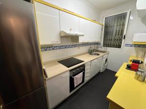 una pequeña cocina con armarios blancos y nevera. en Bonito apartamento muy céntrico, en Bilbao