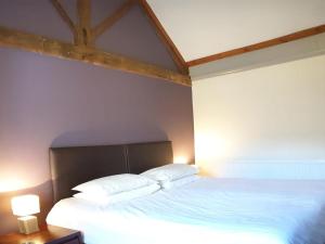 een slaapkamer met een bed met witte lakens en kussens bij Fitling Cottage in Garton