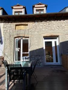 un patio con tavolo in vetro e sedie di fronte a un edificio di Apartamento Arce II en al Valle de Benasque a Castejón de Sos