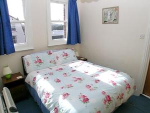 a bedroom with a bed with a flowered comforter and two windows at Sky Lark in Cromer