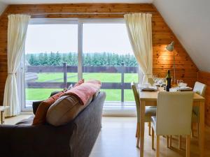 a living room with a couch and a table and a large window at Glenlivet View in Auchnastank