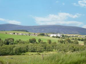 a green field with trees and mountains in the background at Glenlivet View in Auchnastank