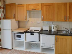a kitchen with white appliances and wooden cabinets at Maddy Cart House in Commondale