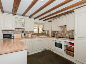 オールストンにあるWild Goose Cottageの白いキャビネットと木製の天井が備わるキッチン