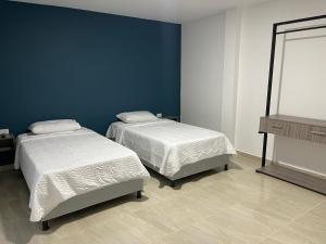 2 camas en una habitación con una pared azul en Work space Hostal, en Uribia