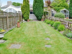 a backyard with a wooden fence and grass at Ivy Cottage in Westgate-on-Sea
