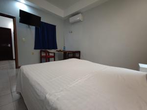 um quarto com uma cama branca e uma televisão em Hotel Cañada Internacional em Palenque