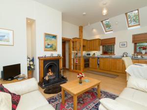 a living room with a fireplace and a kitchen at Seabird Cottage in Broadford