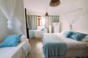 a bedroom with two beds with blue and white at Vila Luz in Caraíva