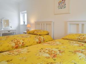 2 camas en una habitación con colchas amarillas en Llifon en Llanwnda