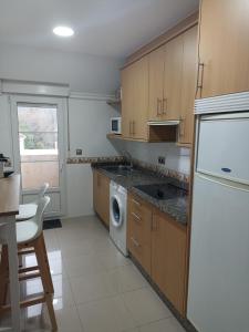 eine Küche mit einem weißen Kühlschrank und einem Geschirrspüler in der Unterkunft EL ATICO in Caldas de Reis