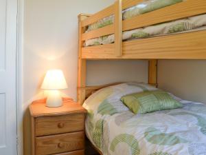a bedroom with a bunk bed and a table with a lamp at Pams Plaice in Offord Cluny