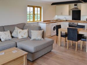 a living room with a couch and a kitchen at Horseshoe Cottage in Alkham