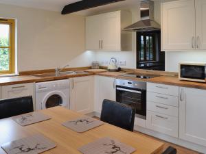 a kitchen with white cabinets and a table with chairs at Horseshoe Cottage in Alkham
