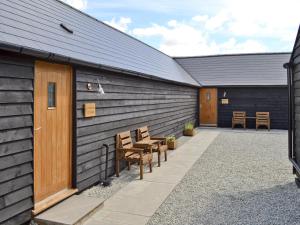 a patio with wooden benches next to a building at Horseshoe Cottage in Alkham
