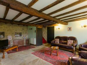 a living room with leather couches and a tv at Highbury Cottage in Hathersage