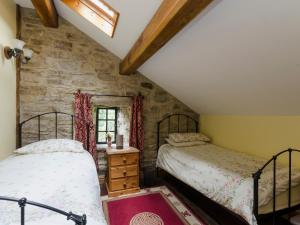 2 Betten in einem Zimmer mit einer Steinmauer in der Unterkunft Highbury Cottage in Hathersage