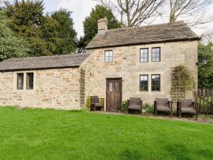 an old stone house with benches in a yard at Highbury Cottage in Hathersage