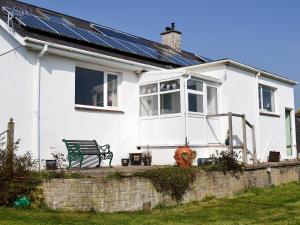 a white house with solar panels on the roof at Encil-y-mor in Criccieth